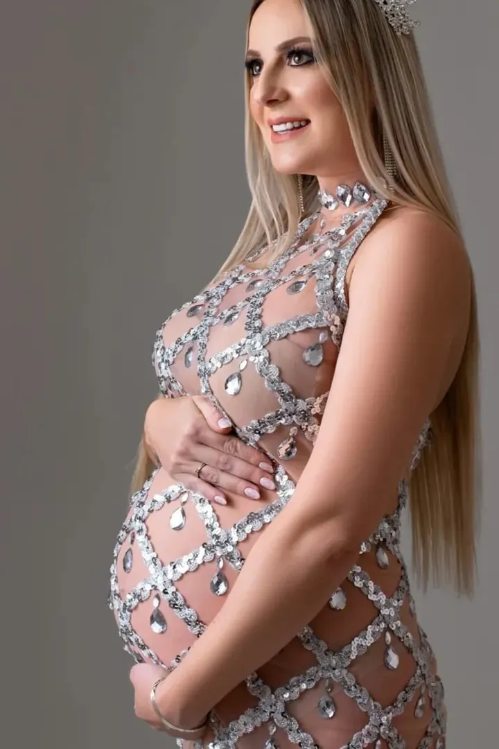 Gestante de vestido bordado e coroa, maquiada